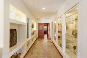 Hallway featuring built in shelves, recessed lighting, and stone tile floors