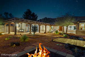 Back of house at twilight with stucco siding, a patio area, a fire pit, and a pergola