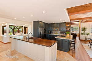 Kitchen with a breakfast bar area, beam ceiling, tasteful backsplash, a peninsula, and dark stone countertops