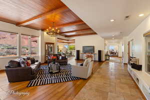 Living room featuring light wood finished floors, a wood ceiling with exposed beams, recessed lighting, and a chandelier