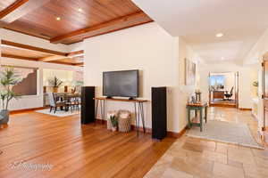 Living room featuring recessed lighting, light wood finished floors, and a wooden ceiling with exposed beams
