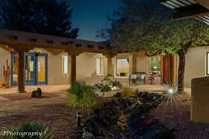 Back of house at night with a patio area and stucco siding