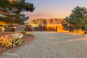 Pueblo revival-style home featuring a gate, a mountain view, stucco siding, a fenced front yard, and gravel driveway