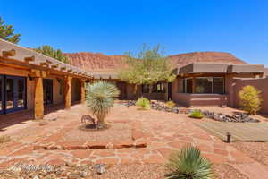 Pueblo-style home with a patio area, stucco siding, a mountain view, french doors, and a pergola