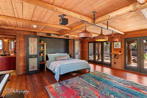 Bedroom with wooden walls, french doors, dark wood finished floors, access to outside, and a wooden ceiling with exposed beams