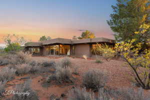 View of front of home featuring stucco siding, a chimney, and a patio area
