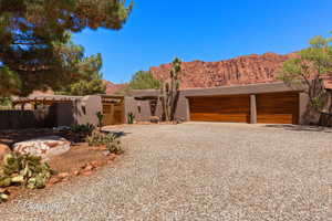 Pueblo-style home featuring a gate, a mountain view, stucco siding, and driveway