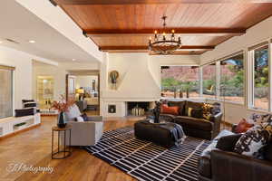 Living room with a wood ceiling with exposed beams, a chandelier, light wood-style floors, and a fireplace