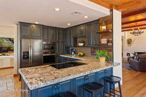 Kitchen featuring open shelves, backsplash, appliances with stainless steel finishes, a kitchen bar, and light stone counters