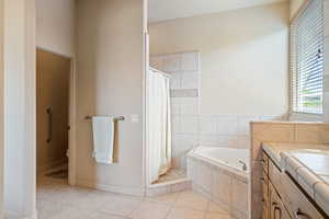Bathroom featuring light tile patterned floors, vanity, a bath, and a shower stall