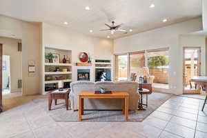 Living area with recessed lighting, a glass covered fireplace, built in features, light tile patterned flooring, and ceiling fan