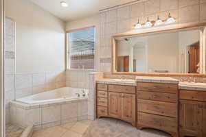 Bathroom with double vanity, a garden tub, light tile patterned floors, tile walls, and recessed lighting