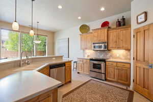 Kitchen featuring appliances with stainless steel finishes, pendant lighting, light tile patterned flooring, tasteful backsplash, and recessed lighting