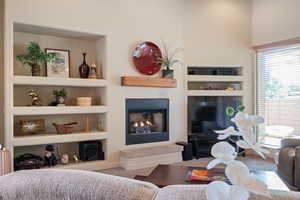 Living area featuring built in shelves, a lit fireplace, and carpet flooring