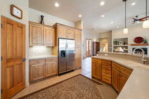 Kitchen with stainless steel refrigerator with ice dispenser, recessed lighting, decorative backsplash, light tile patterned floors, and hanging light fixtures