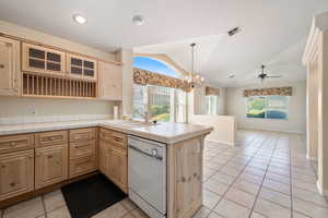 Kitchen with light tile patterned flooring, vaulted ceiling, dishwasher, a chandelier, and healthy amount of natural light