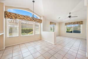 Unfurnished dining area featuring vaulted ceiling, light tile patterned floors, and ceiling fan