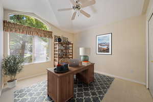 Carpeted home office featuring lofted ceiling and ceiling fan