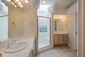 Bathroom featuring two vanities, light tile patterned flooring, and a stall shower