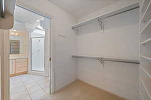 Spacious closet with light tile patterned floors and light colored carpet