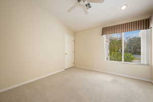 Carpeted empty room featuring lofted ceiling and ceiling fan