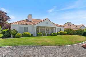 View of front of house featuring stucco siding, a front yard, a tiled roof, and a chimney