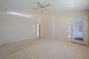 Unfurnished room featuring vaulted ceiling, light colored carpet, and a ceiling fan