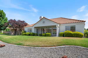 Rear view of house with a lawn, a chimney, stucco siding, and a tiled roof