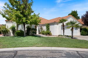 Mediterranean / spanish-style house featuring a tile roof, a front yard, stucco siding, an attached garage, and driveway