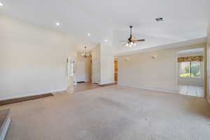 Unfurnished living room with light carpet, a ceiling fan, a chandelier, high vaulted ceiling, and recessed lighting