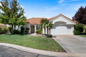 Mediterranean / spanish home featuring driveway, stucco siding, a front yard, a tiled roof, and a garage