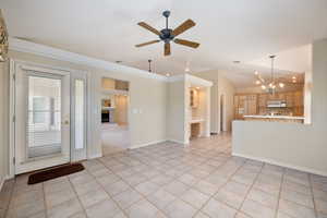 Unfurnished living room with a fireplace with raised hearth, light tile patterned floors, a chandelier, a ceiling fan, and lofted ceiling