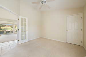 Unfurnished room featuring light colored carpet, a ceiling fan, and light tile patterned floors