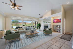 Tiled living room featuring carpet flooring, high vaulted ceiling, a tiled fireplace, and ceiling fan