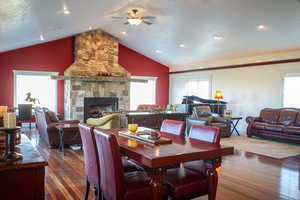 Dining space with a stone fireplace, dark wood finished floors, healthy amount of natural light, and lofted ceiling