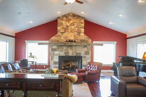 Living room featuring dark wood finished floors, a fireplace, lofted ceiling, recessed lighting, and ceiling fan