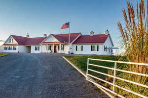 View of front facade with a metal roof, covered porch, and a chimney