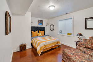 Bedroom featuring a textured ceiling and finished concrete floors
