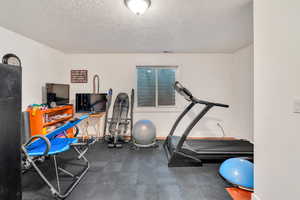 Workout area featuring a textured ceiling and baseboards