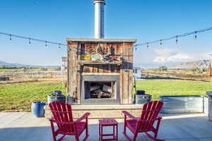 View of patio featuring an outdoor fireplace, a mountain view, and a view of rural / pastoral area
