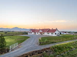 View of front of home with driveway, a chimney, and a view of rural / pastoral area