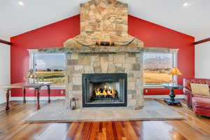 Living area with wood finished floors, a stone fireplace, recessed lighting, and high vaulted ceiling