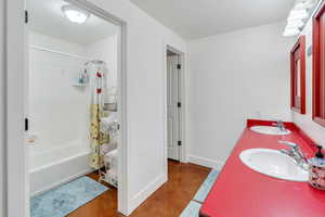 Bathroom with shower / tub combo, double vanity, concrete flooring, and a textured ceiling
