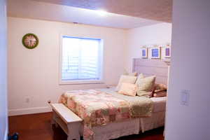 Bedroom with a textured ceiling and dark wood-style floors