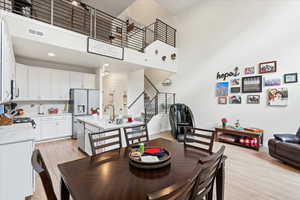 Dining area with a high ceiling, stairway, and light wood-style floors