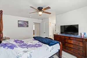 Bedroom featuring light colored carpet, a textured ceiling, and a ceiling fan