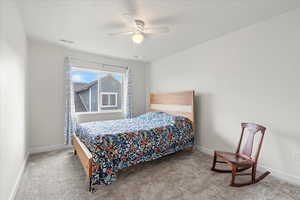 Carpeted bedroom with a ceiling fan and baseboards