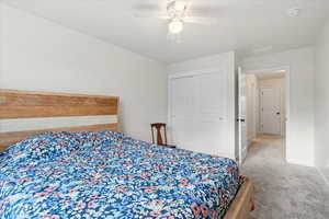 Bedroom with light carpet, a ceiling fan, and a closet