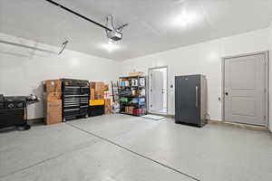 Garage featuring freestanding refrigerator and a garage door opener