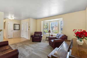 Living area with light colored carpet and a textured ceiling